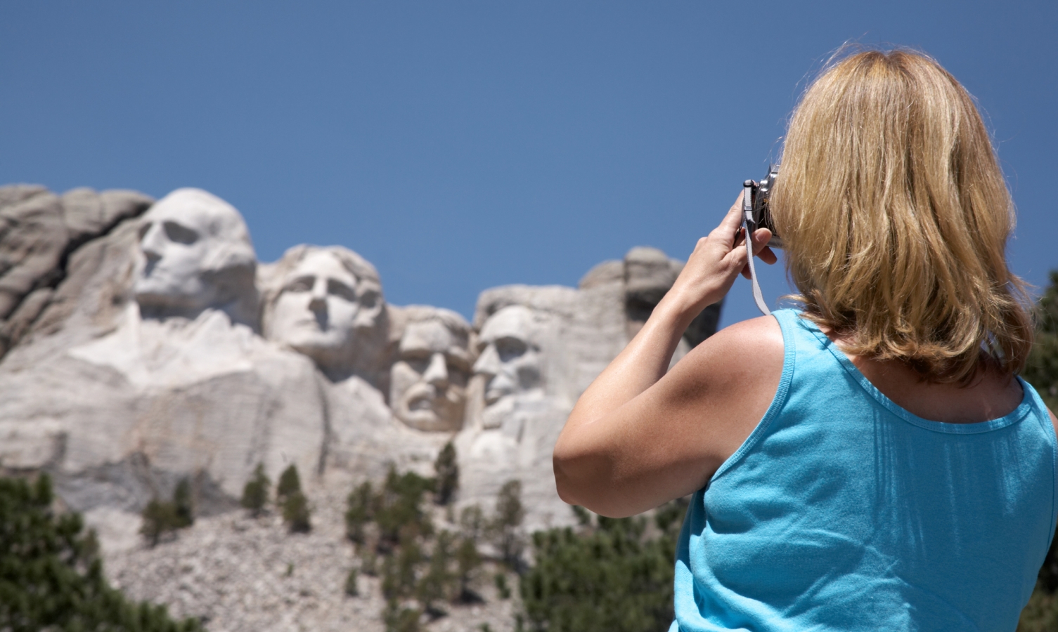 Woman takes a snapshot of Mt. Rushmore while on a summer vacation